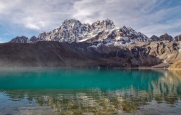 Group of trekkers hiking along the scenic Affordable gokyo trek trail with snow-capped mountains and turquoise lakes in background.