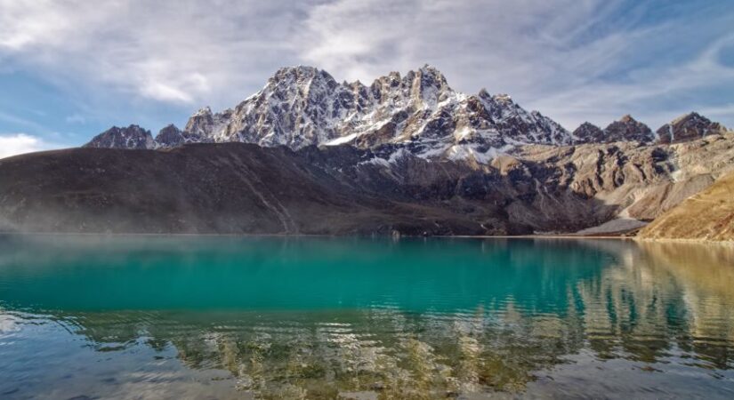 Group of trekkers hiking along the scenic Affordable gokyo trek trail with snow-capped mountains and turquoise lakes in background. 