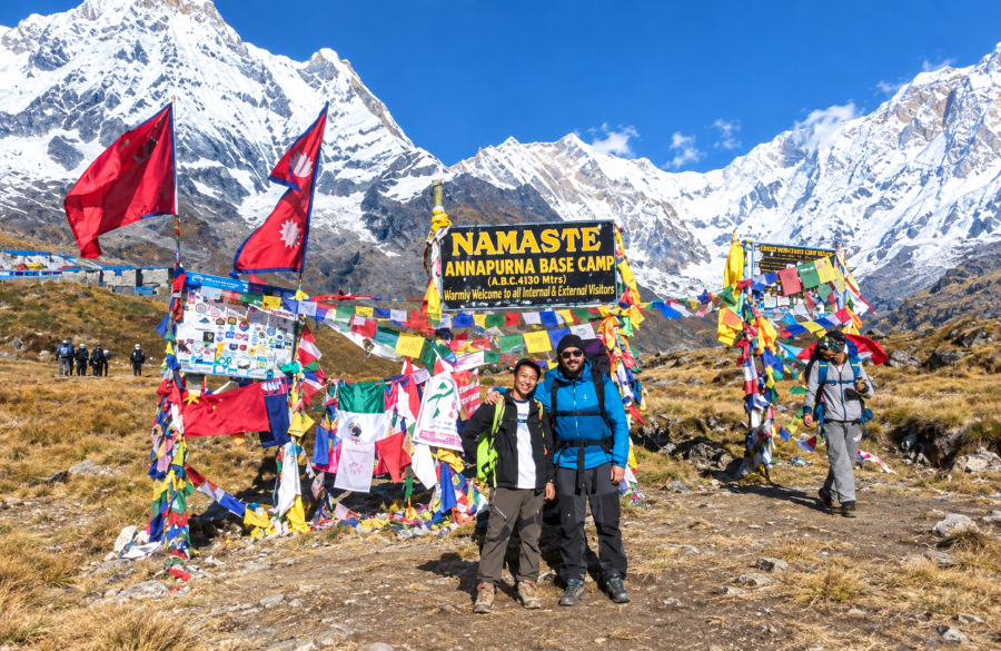 Annapurna Base Camp with snow-capped Himalayan mountains, prayer flags, and trekkers under a clear blue sky
