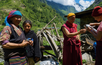 Traditional mountain village scene with local people and trekkers in the Himalayas